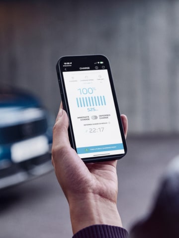 Kobieta ze smartfonem na tle PEUGEOT E‑3008 Dual Motor