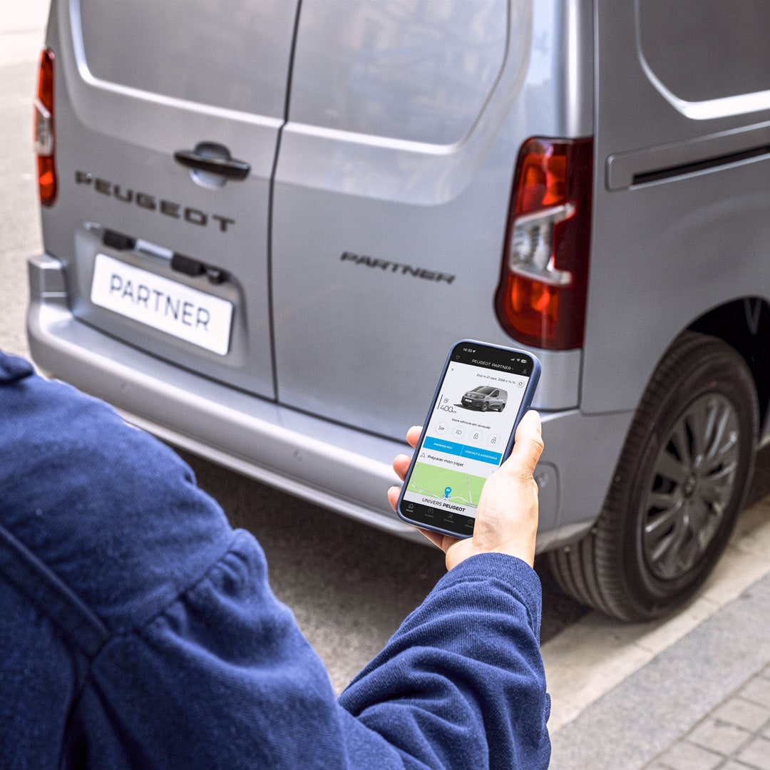Kobieta używająca smartfona za PEUGEOT Partner